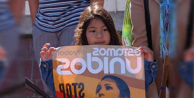 一个孩子举着写着“estamos unidos”的牌子。
